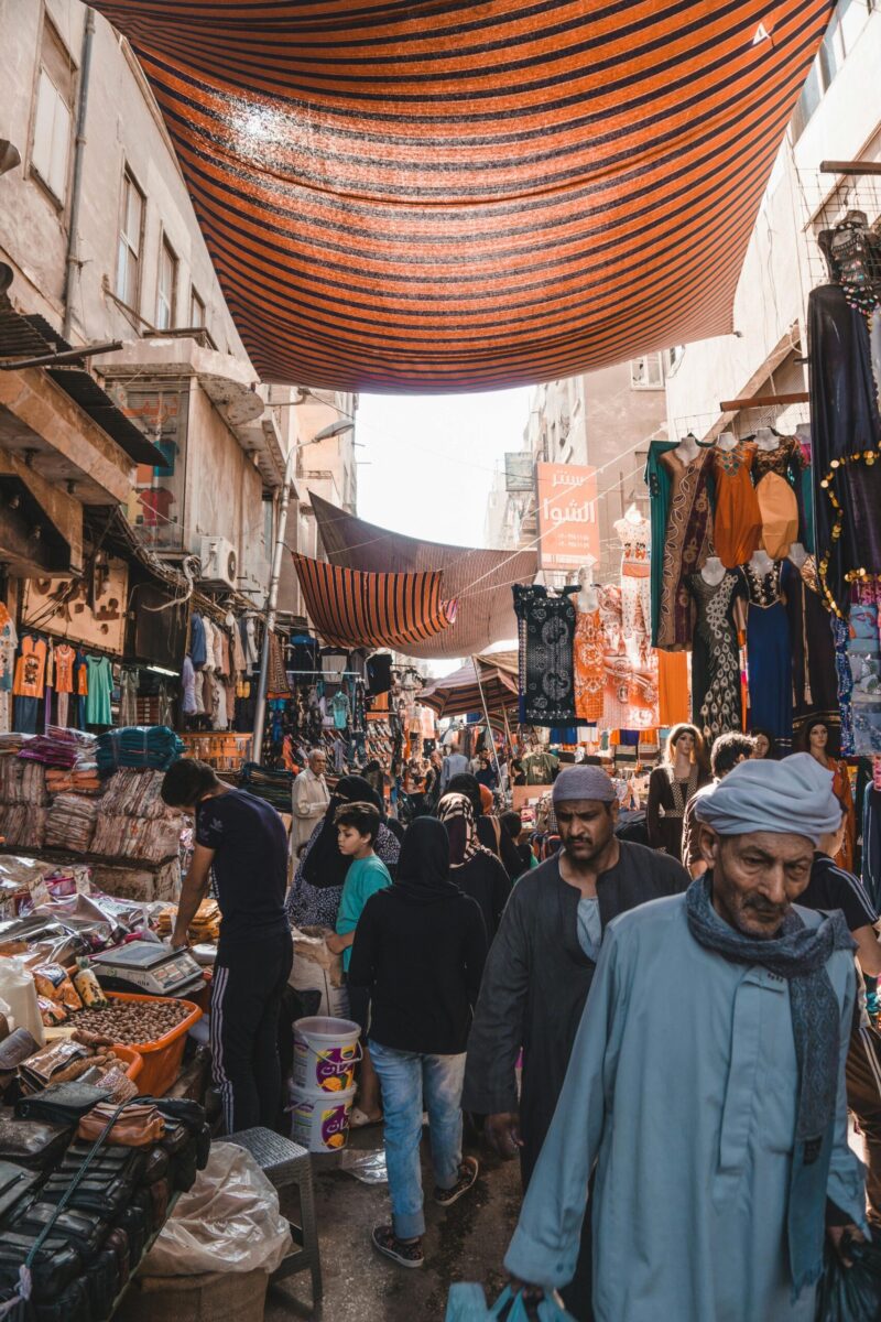 Vibrant marketplace in Cairo with people shopping under striped canopies.